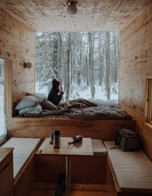 person sitting in a tiny home in a forest in the winter